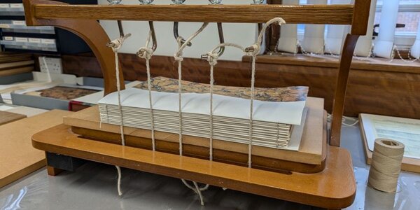 Tudalennau llawysgrif wedi'u casglu a'u gwasgu mewn rhwymwr pren