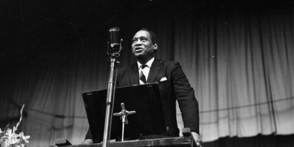 Paul Robeson yn sefyll ar lwyfan