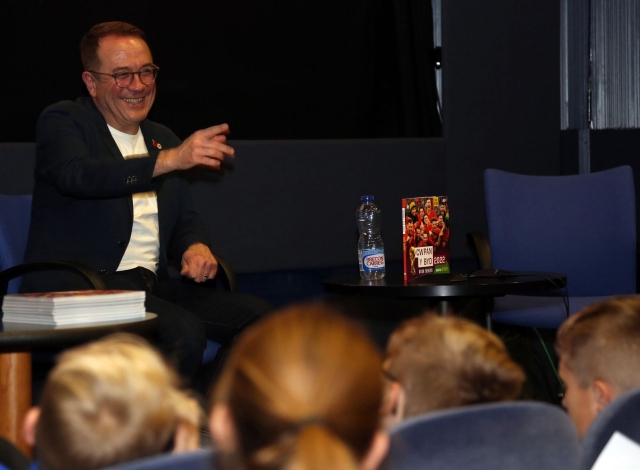 Dylan Ebenezer yn siarad â disgyblion o'r llwyfan yn y Drwm yn y Llyfrgell Genedlaethol h